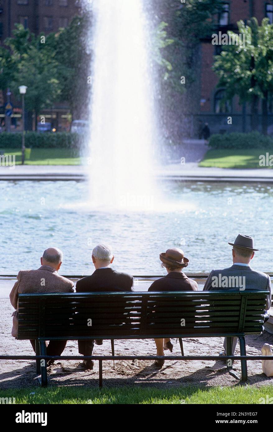 In den 1960er Jahren. Eine Gruppe von vier älteren Menschen sitzt auf einer Bank mit Blick auf einen Brunnen. Schweden Juli 1967 Kristoffersson CV52-6 Stockfoto