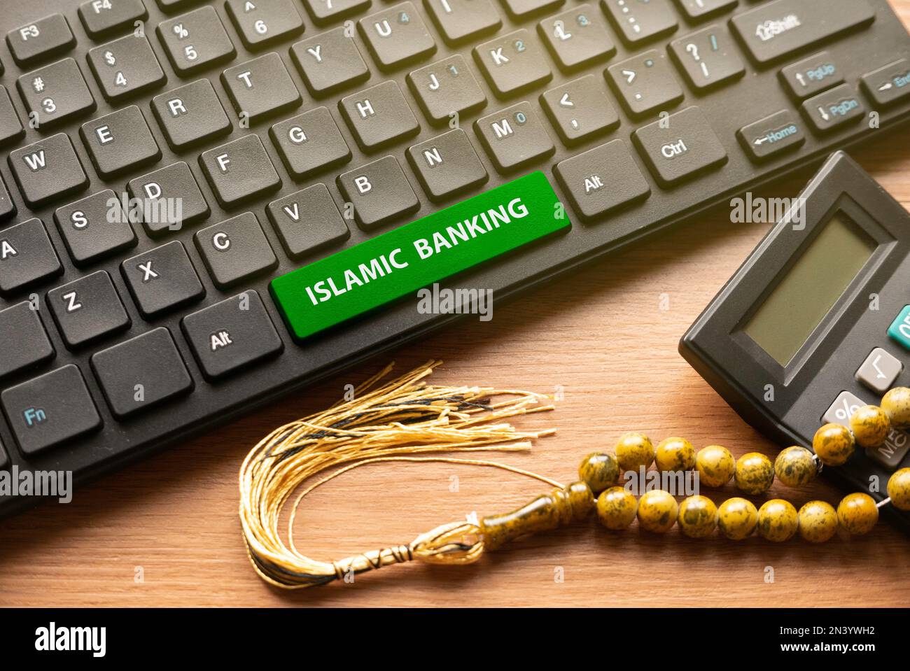 Taschenrechner, Rosenkranz-Perlen und Computertastatur mit grünem Knopf, geschrieben mit Islamic Banking. Stockfoto