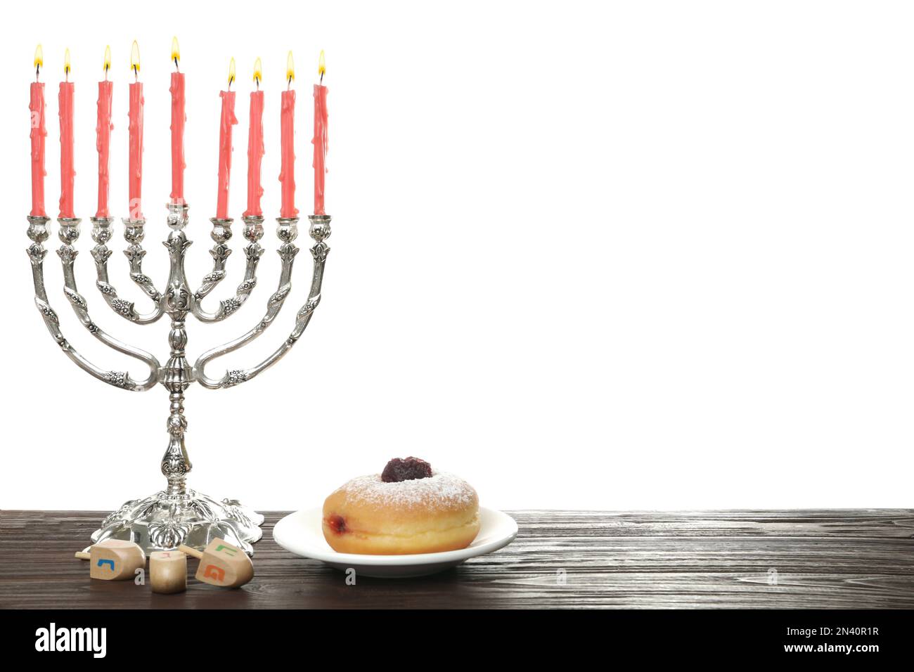 Silberne Menora nahe Sufganiyah und Dreidel mit den Symbolen Nun, He, PE, Gimel auf weißem Hintergrund Stockfoto