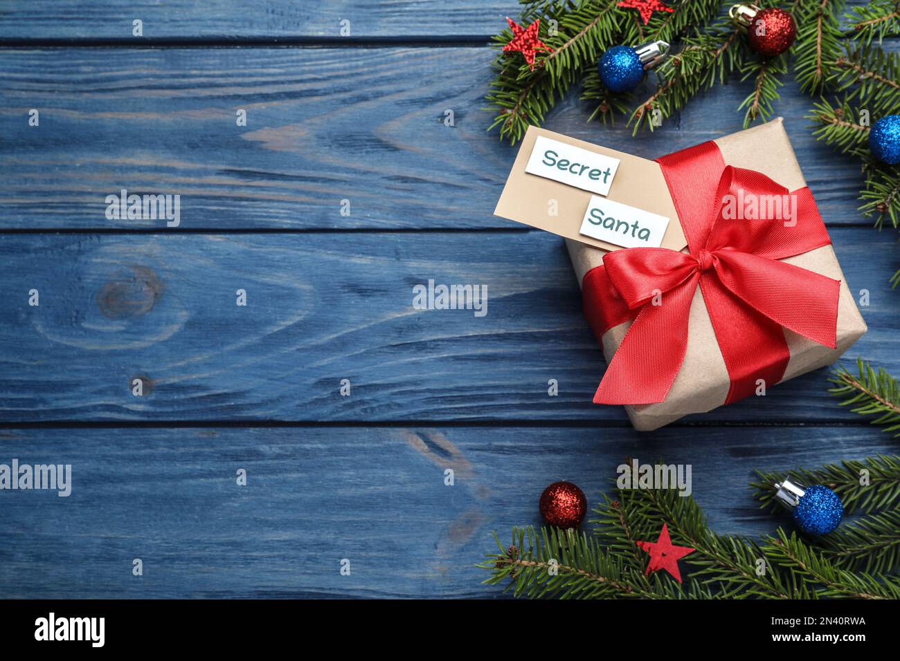 Flach liegend mit Geschenk vom geheimen Weihnachtsmann auf blauem Holztisch, Platz für Text Stockfoto