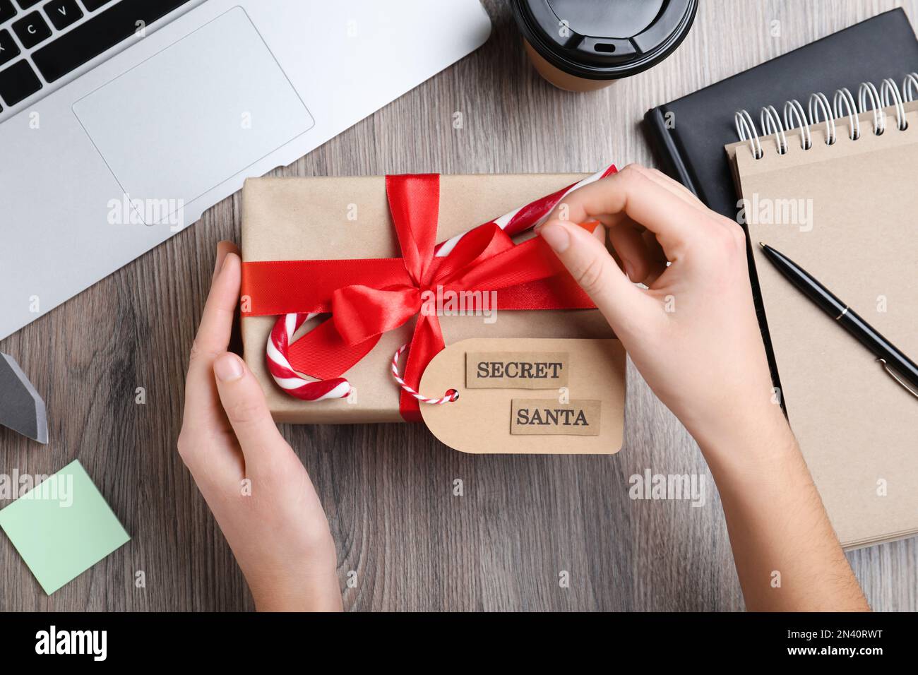 Frau, die ein Geschenk vom geheimen Weihnachtsmann am Arbeitsplatz eröffnet, Draufsicht Stockfoto