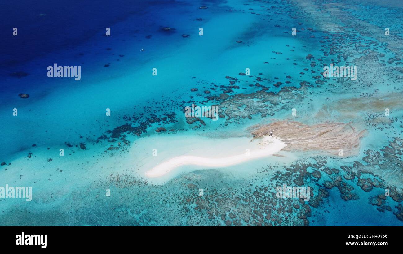 Kleine sandkiste mit einer abgelegenen Wetterstation umgeben von einem Riff im Korallenmeer vor Australien mit einem Segelboot in der Nähe Stockfoto