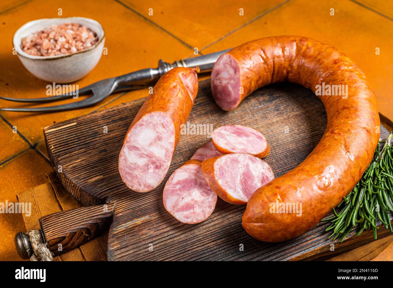 Krakau Räucherwurst mit Rosmarin und Gewürzen auf einem Holzbrett.  Orangefarbener Hintergrund. Draufsicht Stockfotografie - Alamy