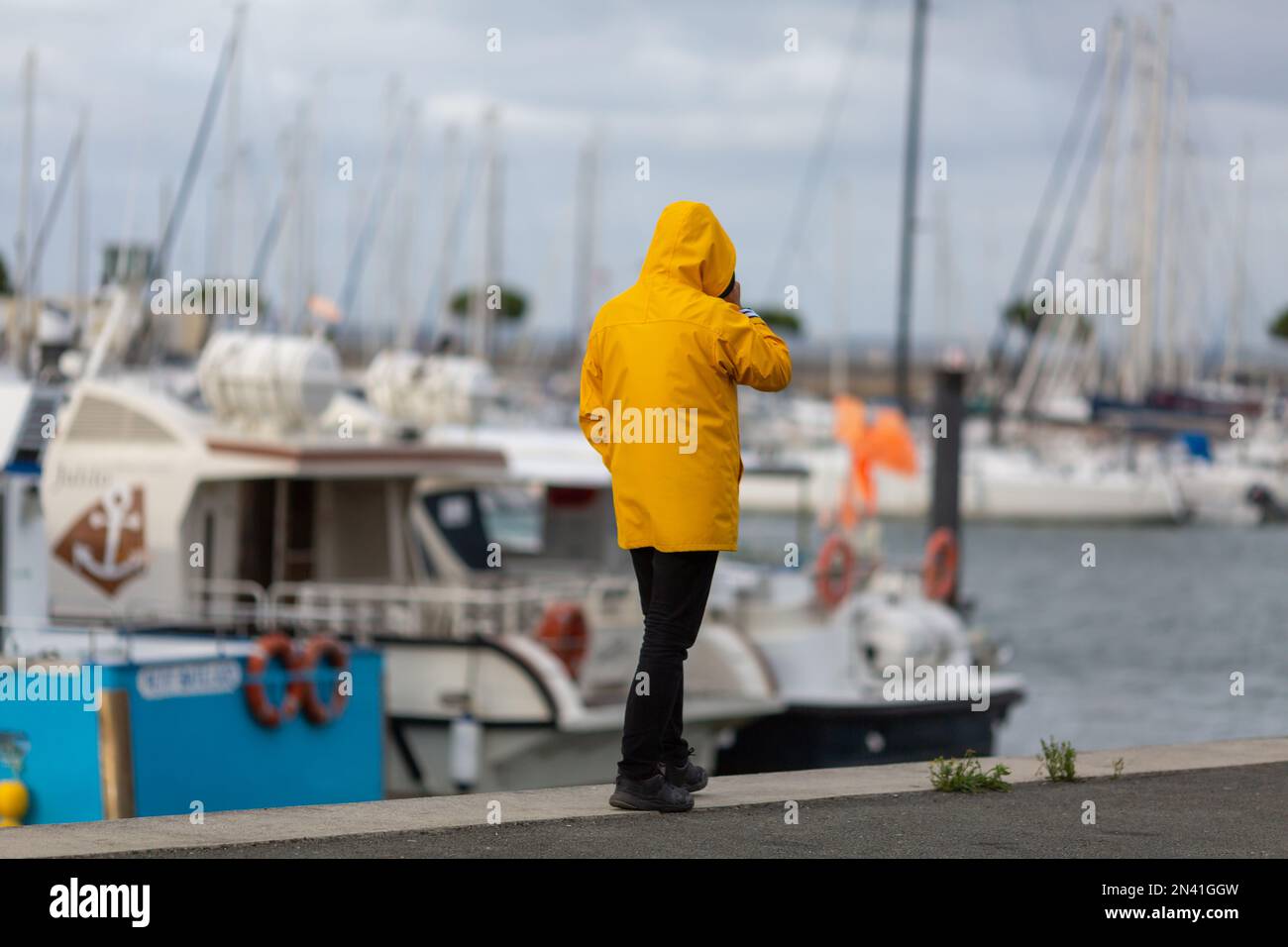 Ein Mann in gelbem Ölfell, der am Fischereihafen entlang spaziert Stockfoto