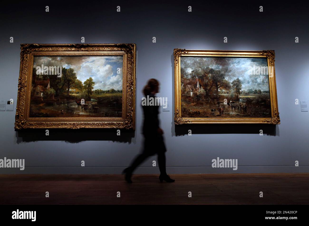 A Victoria and Albert Museum press officer walks past John Constable's The Hay Wain, left, towards the full oil sketch of the same scene at an exhibition entitled: 'Constable: The Making of a Master ' with works by British landscape painter John Constable, during a preview in London, Wednesday, Sept. 17, 2014. Best-known to many for ‘The Hay Wain’ - an artwork which adorns countless decorative plates and trays, the exhibition explores Constable’s influences and takes a look at the creative process behind some of his most famous works. The exhibition will run from Sept. 20, 2014 to Jan. 11. 201 Stockfoto