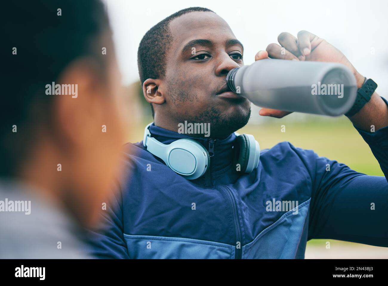 Pause, Fitness und schwarzer Mann trinkt Wasser nach einem Rennen, Training und Sport in einem Stadion in Marokko. Gesundheit, Entspannung und afrikanischer Sportler bei einem Drink Stockfoto