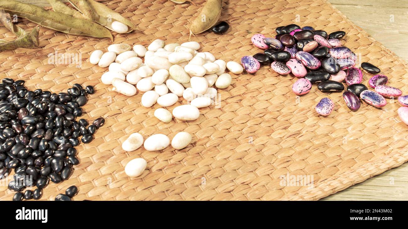 Haufen geschälter Bohnen und leere Hülsen auf einer Strohmatte. Stockfoto