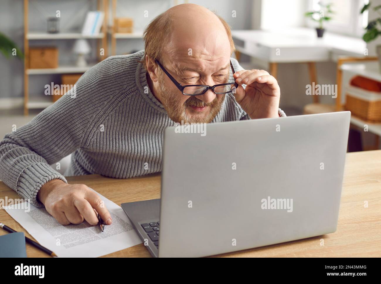 Porträt eines Senioren mit Brille, der auf den Laptop-Bildschirm starrt Stockfoto