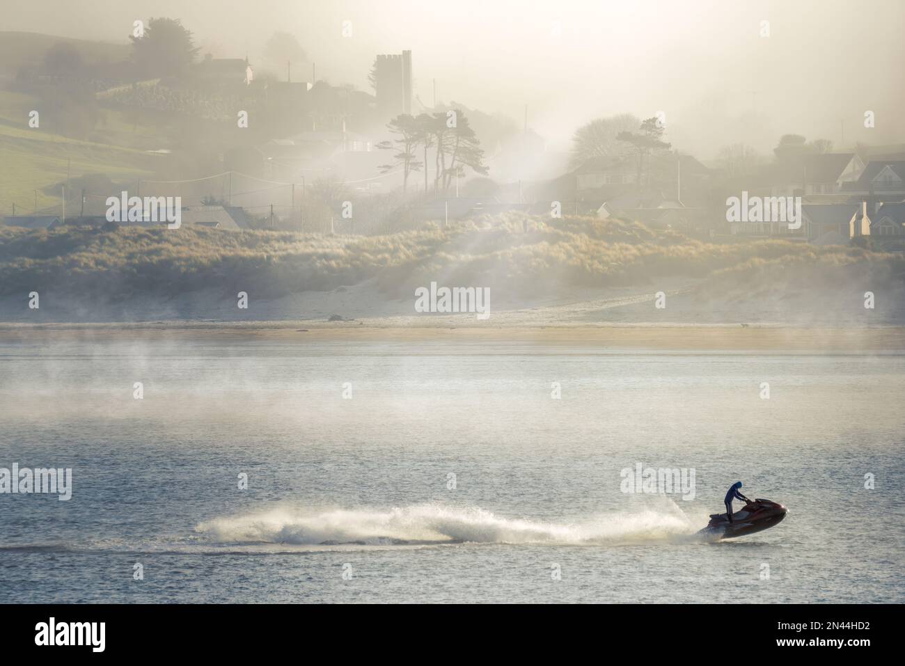 Nach einer weiteren kalten Nacht in North Devon bricht ein Jetski die Ruhe eines nebelverhangenen Flusses Torridge, während die Sonne den tief liegenden Meeresnebel über dem Küstendorf Instow zu verbrennen beginnt. Kredit: Terry Mathews/Alamy Live News Stockfoto