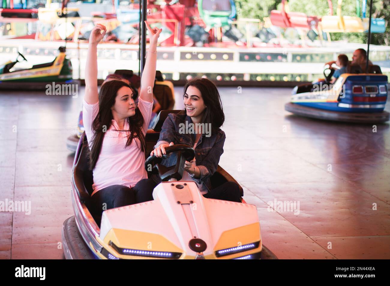 Zwei junge Frauen, die im Sommer eine lustige Autofahrt im Vergnügungspark machen. Stockfoto