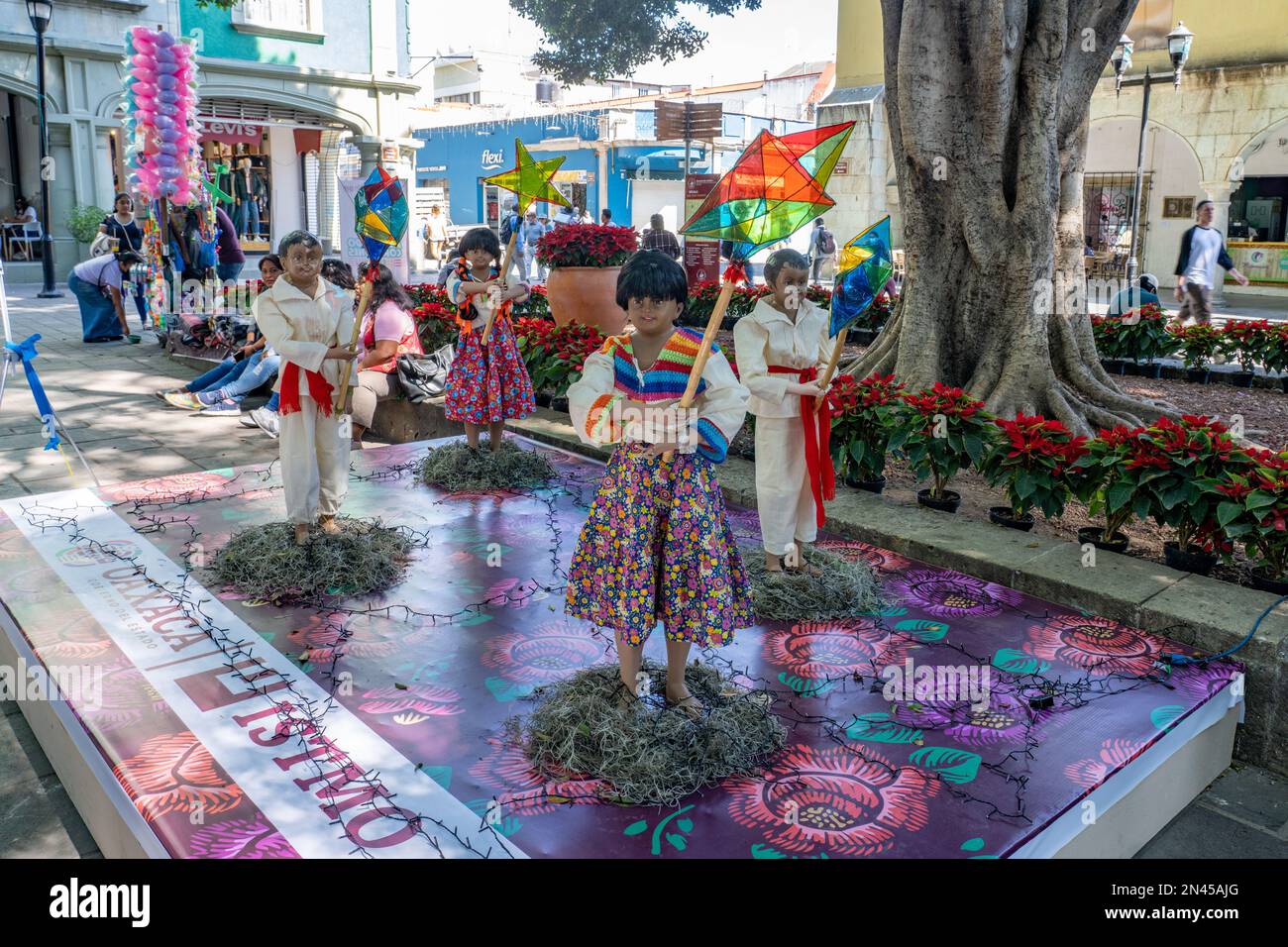 Figuren in regionalen Kleidern der Region Istmo bei einer Weihnachtsausstellung auf dem Zocalo-Platz im historischen Oaxaca, Mexiko. Die Figuren tragen stilisierte Landeerlaubnis Stockfoto