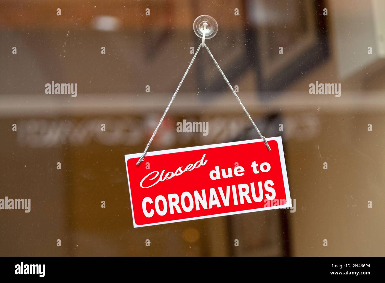 Rotes Schild, das an der Glastür eines Ladens mit der Aufschrift „aufgrund des Coronavirus geschlossen“ hängt. Stockfoto