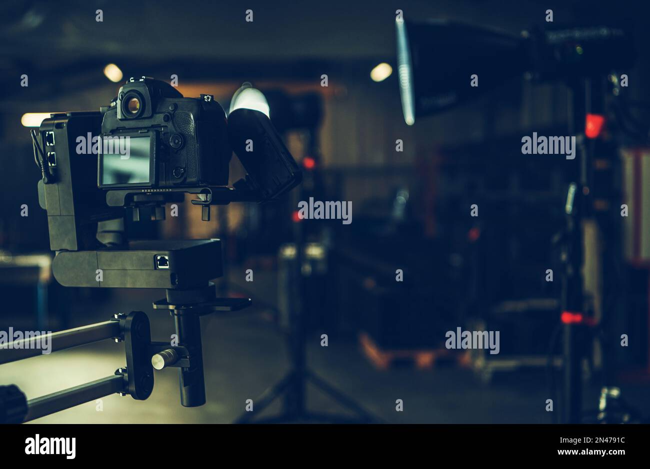 Digitale Videokamera, die an den automatischen Auslegerarm in einem Studio befestigt ist. Professionelle Filmbeleuchtung im Hintergrund Stockfoto