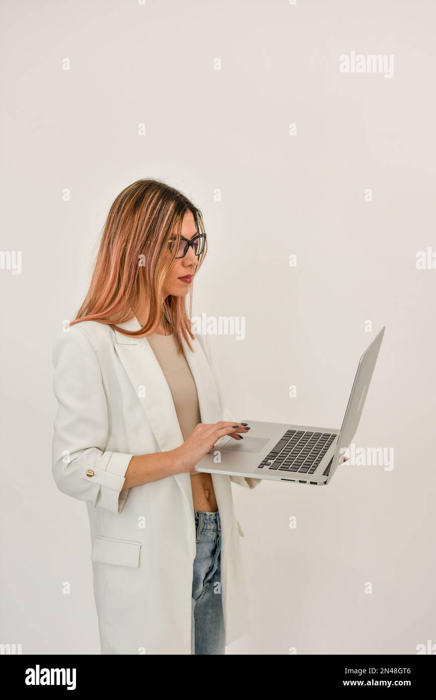 Eine Geschäftsfrau in einer weißen Jacke mit einem grauen Laptop. Stockfoto