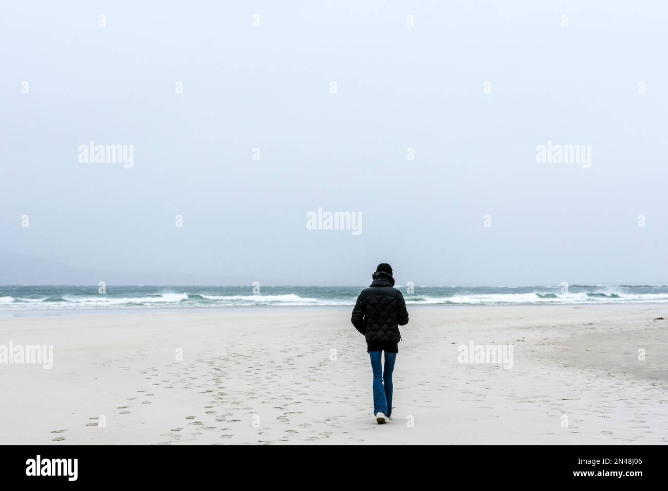 Junge Frau geht allein am Atlantik Stockfoto