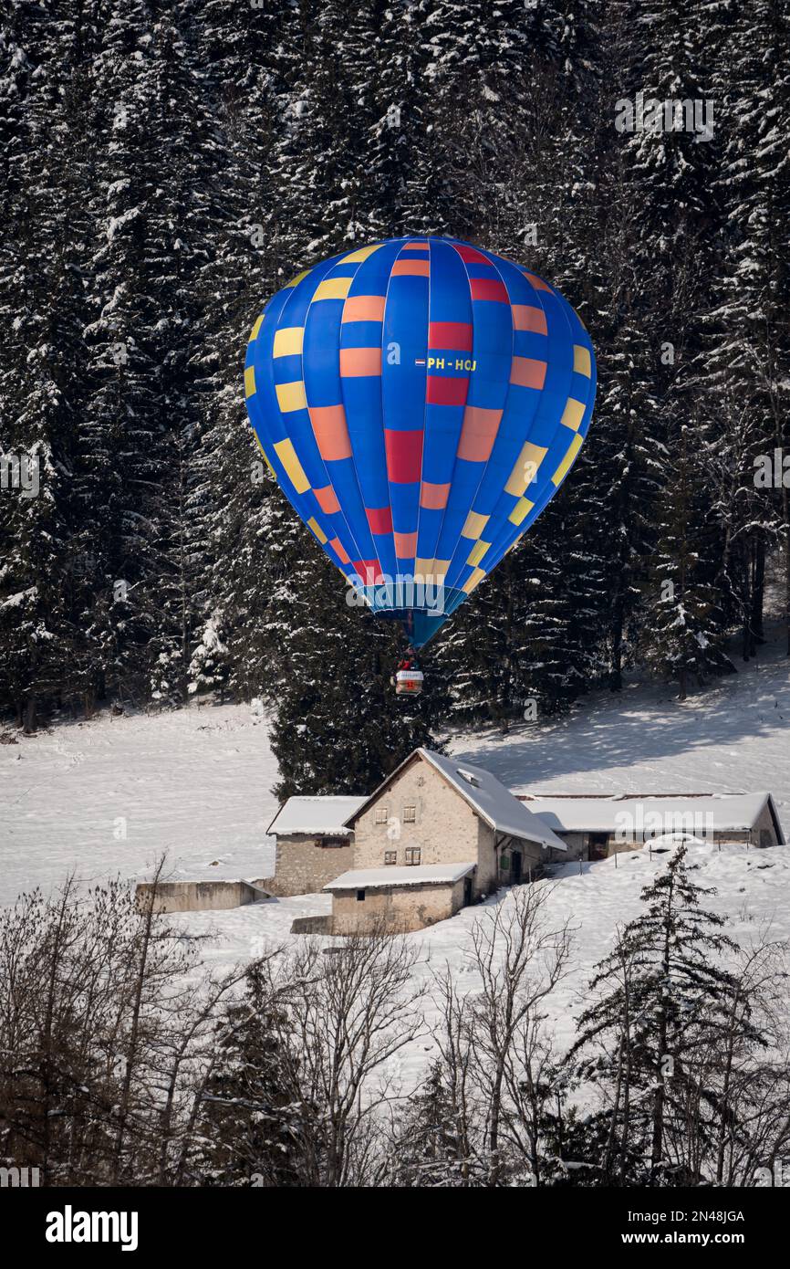 Chateau-d'Oex, Vaud, Schweiz - 23. Januar 2023: Heißluftballonfahrt über dem Haus. Heißluftballonfahrt. Ballonfestival. Stockfoto