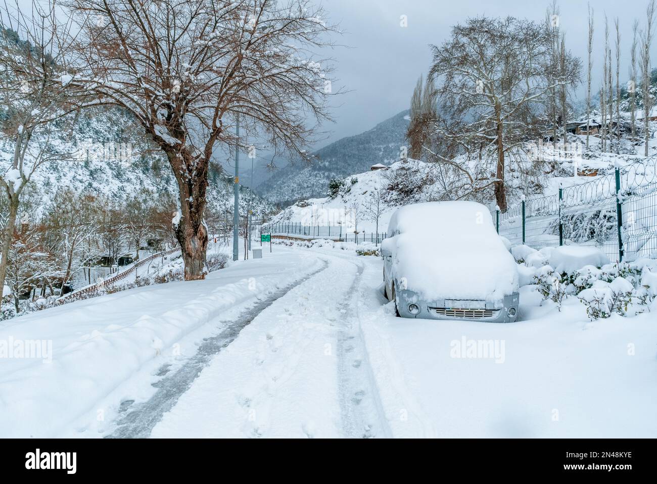 Graues Auto mit Schnee bedeckt im Winter. Eissturmstraße gesperrt und mit Schnee bedeckt. Stockfoto