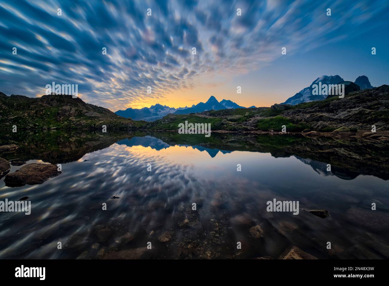 Die Gipfel des östlichen Teils des Mont Blanc-Massivs und einige Wolken spiegeln sich bei Sonnenaufgang in den Lacs des Chéserys. Stockfoto