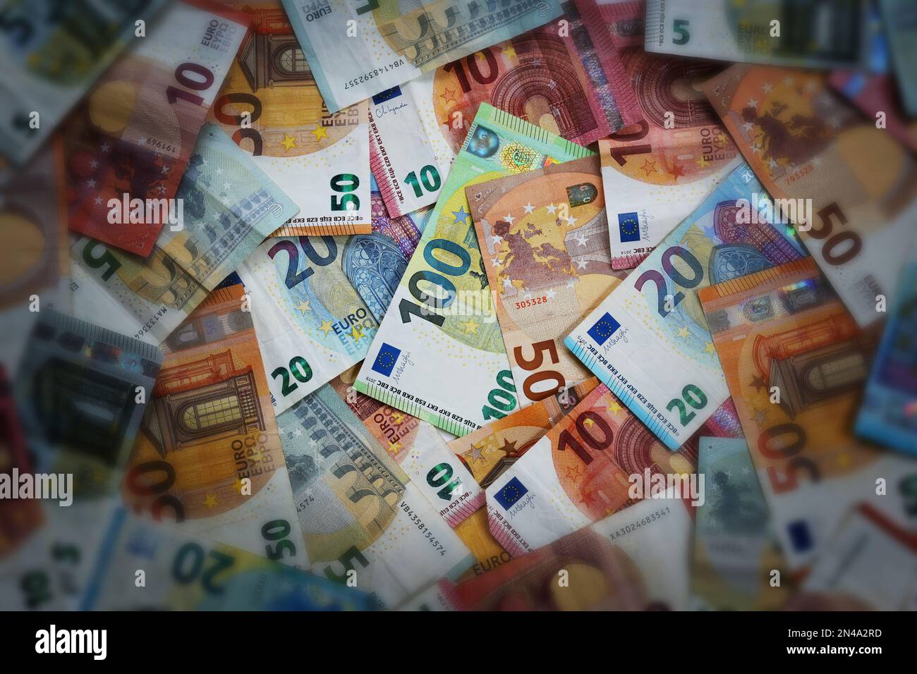 Viele verschiedene Euro-Banknoten, beleuchteter Fokus auf den Hundert-Euro-Schein in der Mitte, dunkel und verschwommen an den Rändern, Konzept für Finanzen, Wirtschaft Stockfoto