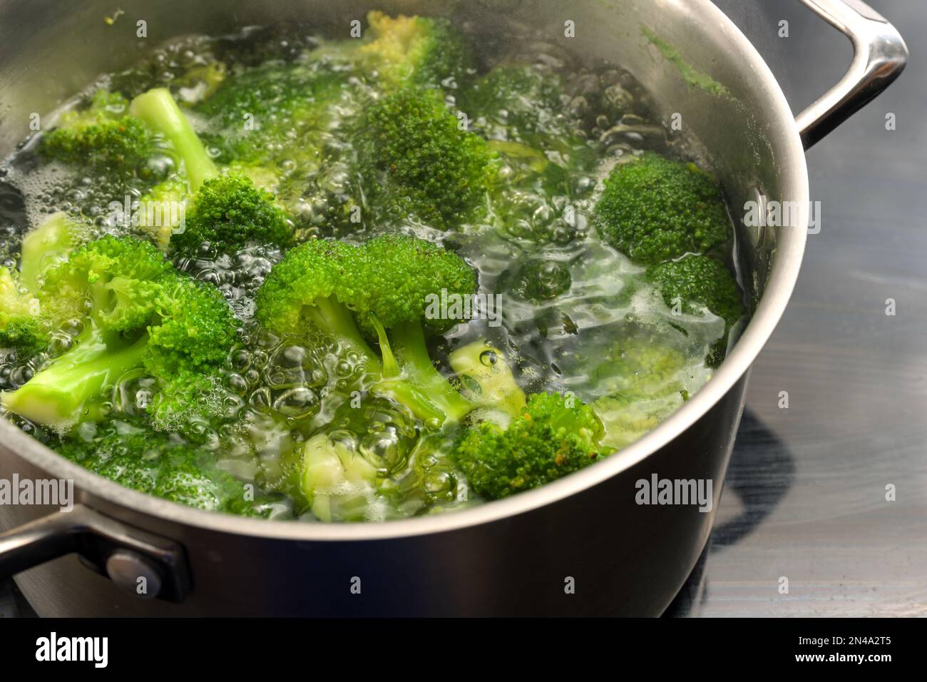 Brokkoli wird in kochendem Wasser in einem Edelstahltopf verborgen, um die frische grüne Farbe zu erhalten, gesundes Kochen mit Gemüse, Kopierraum, selektiert Stockfoto