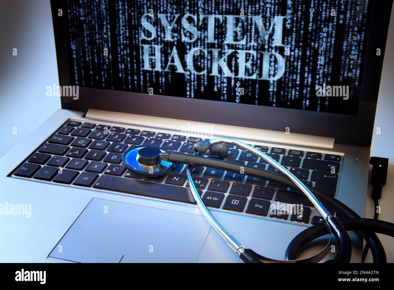 Laptop mit blauer Matrix und NACHRICHTENSYSTEM, DAS ALS Symbol für Cyberkriminalität AUF dem Bildschirm GEHACKT wurde, Stethoskop auf der Tastatur, Konzept für Netzwerksicherheit, Daten Stockfoto