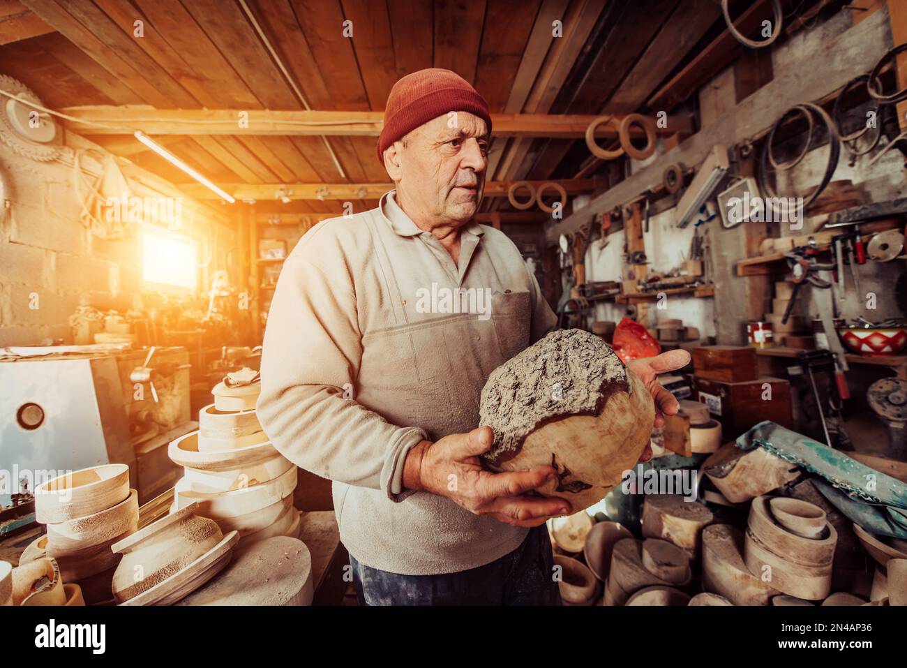 Ein älterer Mann, der Holzprodukte in einer Tischlerwerkstatt verarbeitet Stockfoto