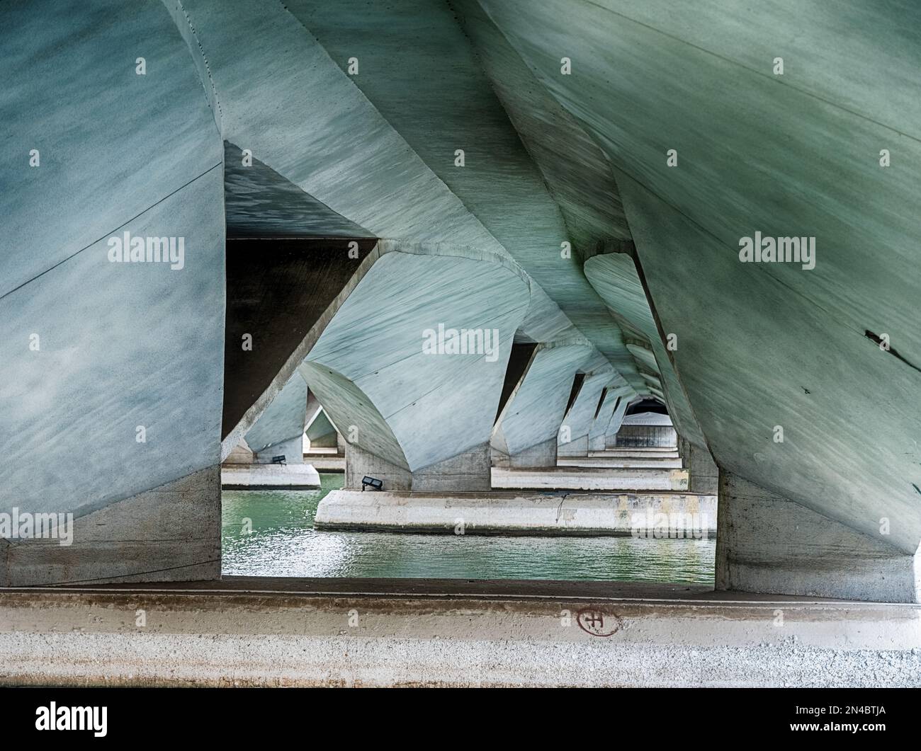 Eine sich wiederholende geometrische Reihe von Grundelementen unterstützt eine Betonbrücke in Singapur. Stockfoto