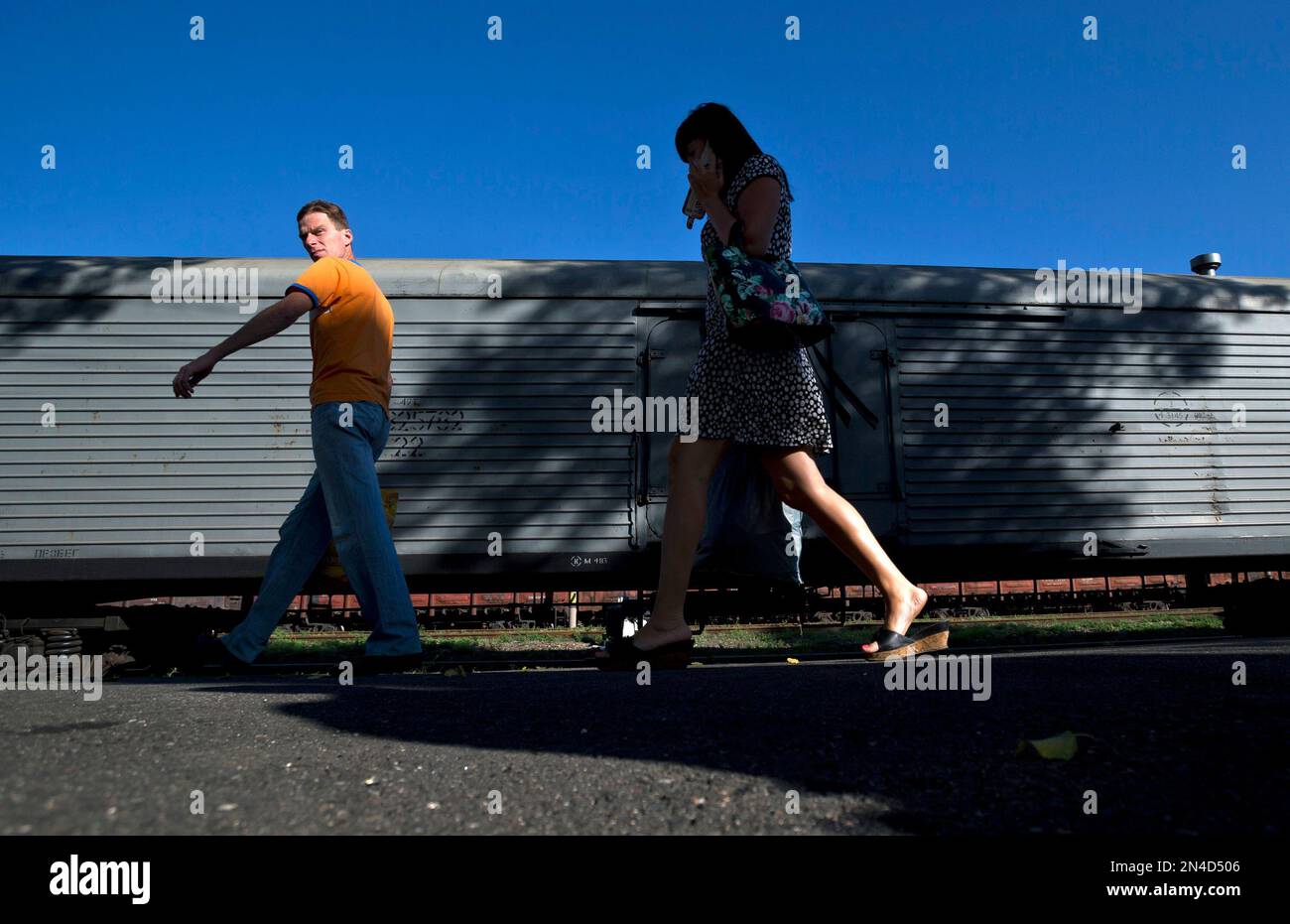 People walk next to a refrigerated train loaded with the bodies of victims, in Torez, eastern