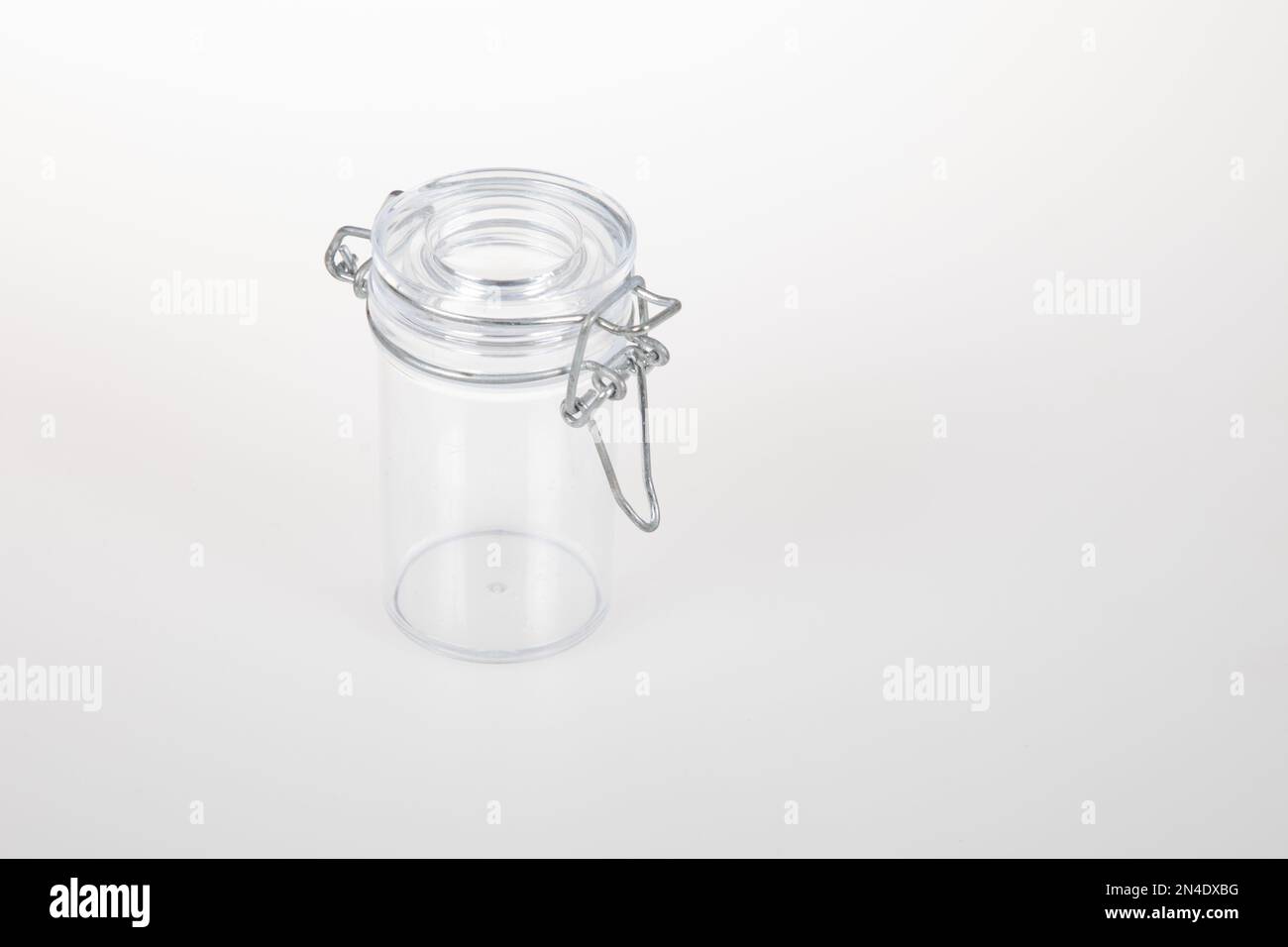 Leerer Glasbehälter mit Metallklemme auf weißem Hintergrund Stockfoto