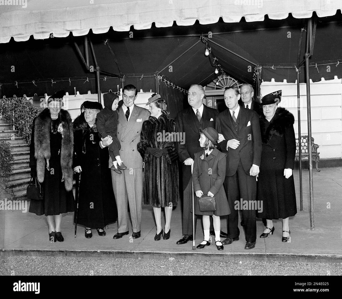 President Franklin D. Roosevelt, first lady Eleanor Roosevelt, and their guests pause for a moment as they leave the White House to attend Christmas Day services at the First Congregational Church in Washington, D.C., Dec. 25, 1940. From left: the first lady; Sara Delano Roosevelt, the president's mother; Franklin Roosevelt III in the arms of his father, FDR Jr.; his wife Ethel du Pont Roosevelt; the president; Diana Hopkins and her father Harry L. Hopkins; Harry Hooker of New York; and Mrs. J.R. Roosevelt, the president's sister-in-law. (AP Photo) Stockfoto