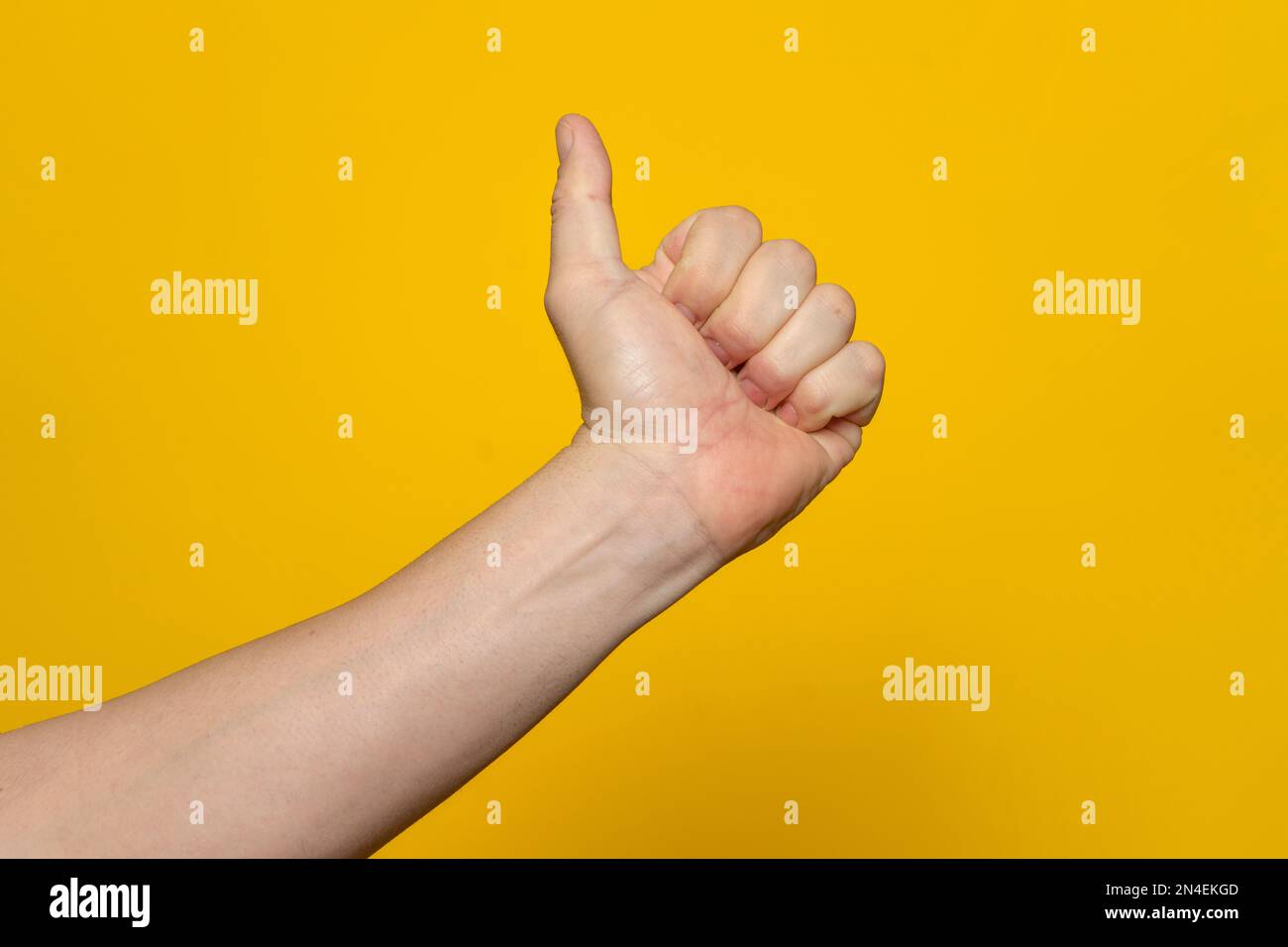 Daumen-hoch-Handzeichen. Die Hand des Mannes zeigt Daumen nach oben, wie, okay, Zustimmung, akzeptieren, Okay, gute, positive Handbewegung. Isoliert auf gelbem Hintergrund Stockfoto