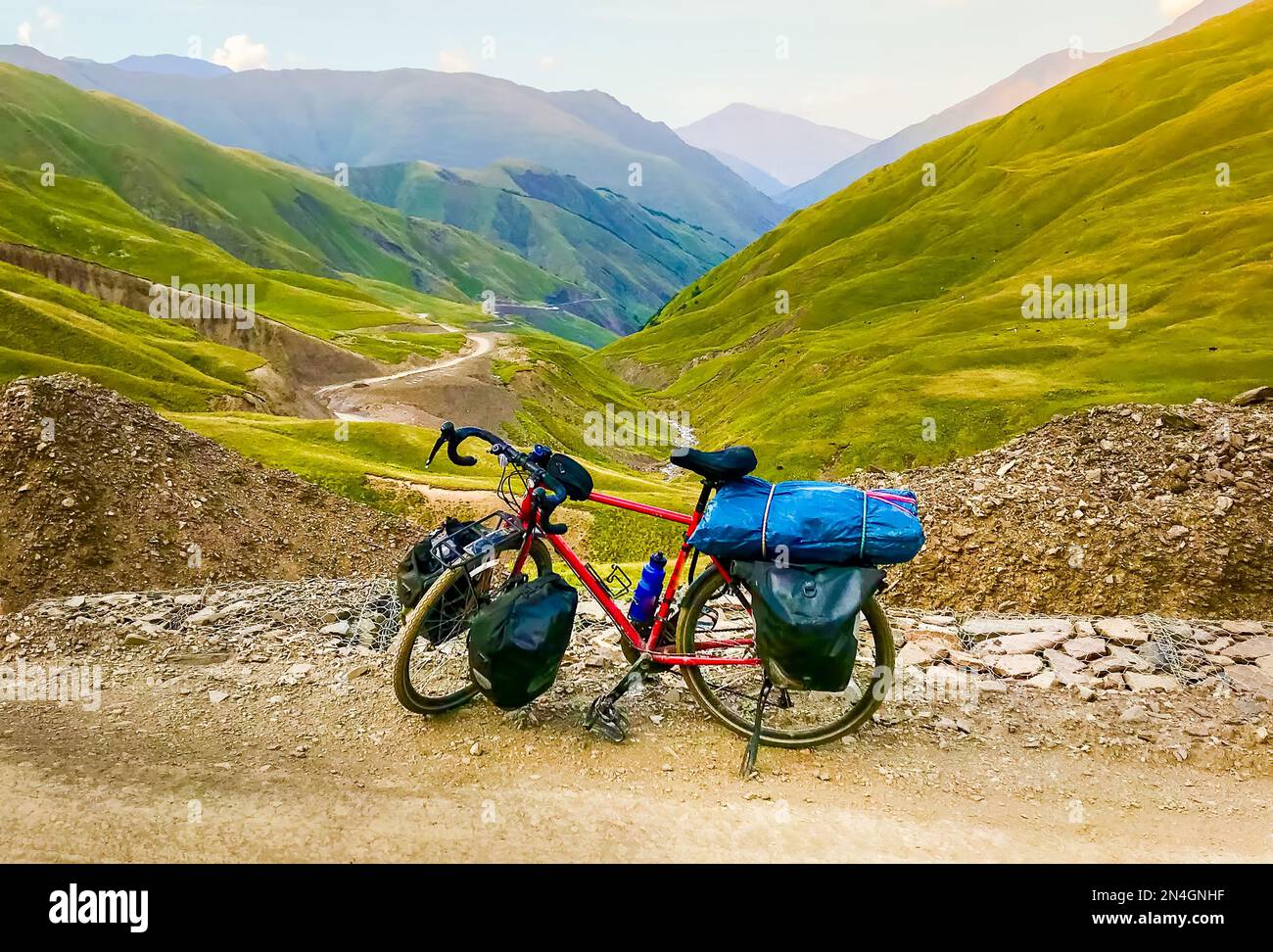 Beladenes rotes Fahrrad mit Zubehör steht im kaukasus und bietet ein wunderschönes Panoramablick auf die Straße Stockfoto