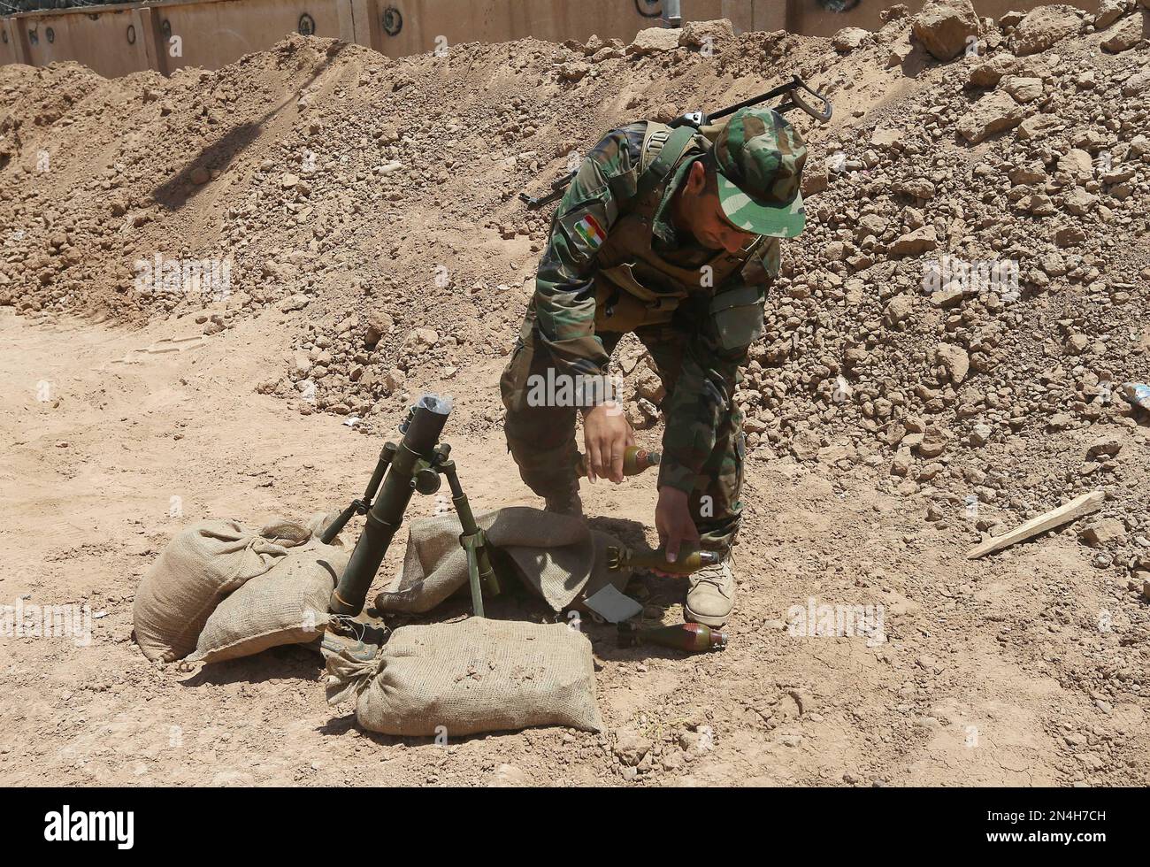 Fighter Shells A Kurdish peshmerga fighter carries mortar shells behind a sand barrier ...