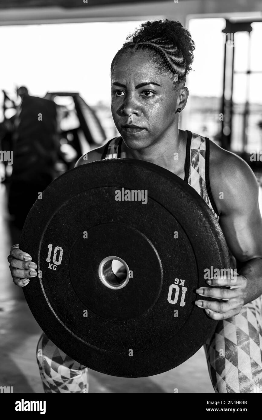 Fitness-Frau, die Kniebeugen mit der Barglocke im Crossfit-Gym macht. Gesundheitskonzept. Stockfoto