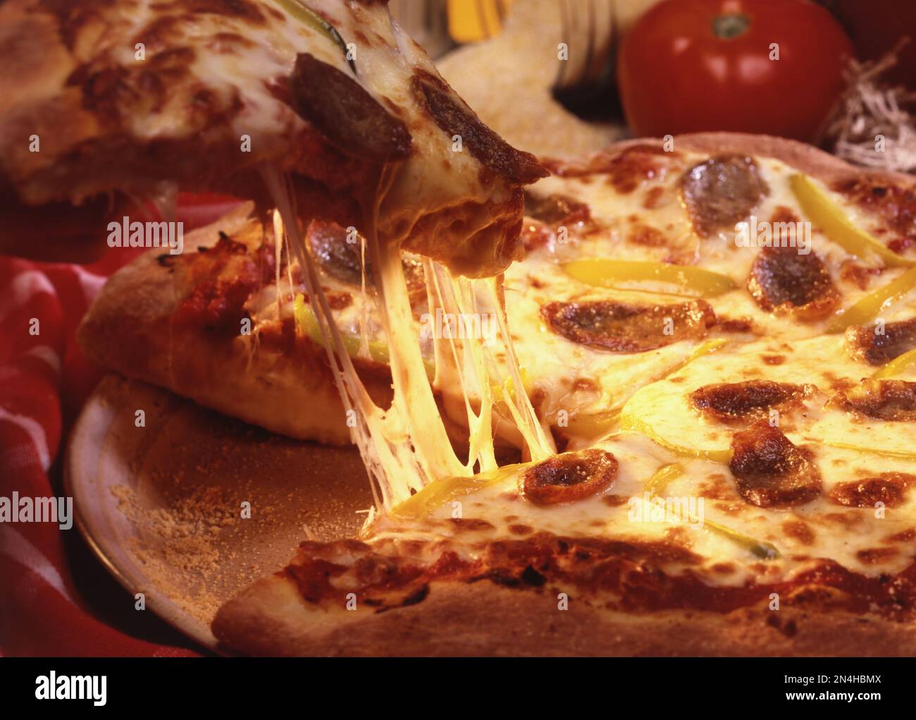 Ich nehme ein Stück Pizza mit heißem, zartem, geschmolzenem, tropfendem Käse. Hintergrundbeleuchtetes horizontales Studiofoto. Stockfoto