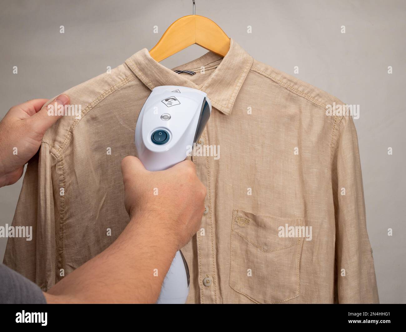 Handdampfer für Kleidung. Ein Hemd wird mit einem tragbaren Bügeleisen  gebügelt. Bügeleisen zum Bügeln von Kleidung Stockfotografie - Alamy