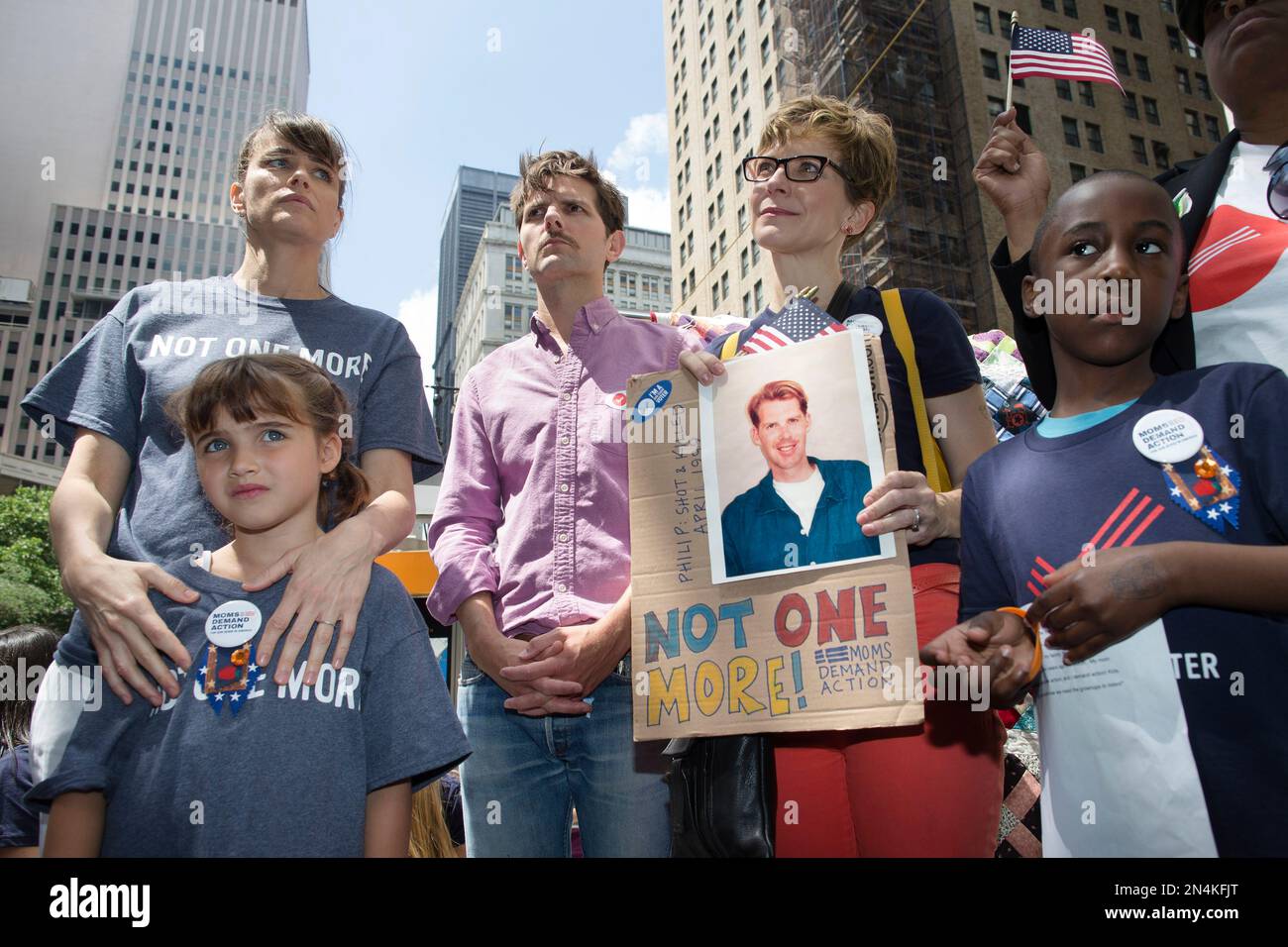 Actress Amanda Peet, left, holds her daughter alongside fellow actor Adam Scott, center, and relatives of gun violence victims at a rally outside city hall to call for tougher gun control laws, Saturday, June 14, 2014, in New York. The protest was underwritten by former New York Mayor Michael Bloomberg, one of the most visible gun control advocates in the U.S., and included relatives of some of those slain in the 2012 shooting rampage at Sandy Hook Elementary School. (AP Photo/John Minchillo) Stockfoto