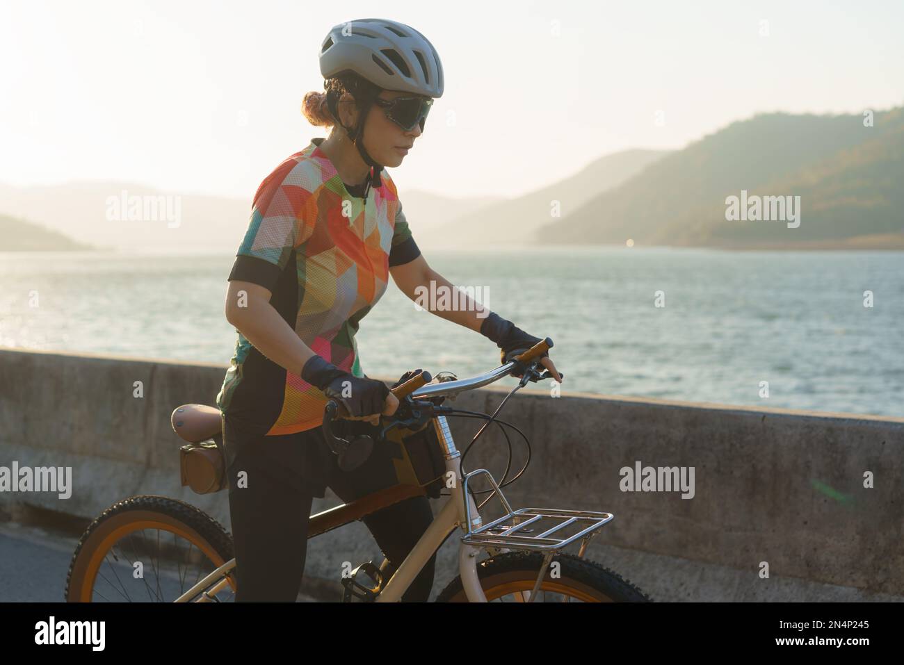 Eine asiatische Radfahrerin bereitet sich am klaren Morgen auf ein Fahrrad um den See vor. Stockfoto
