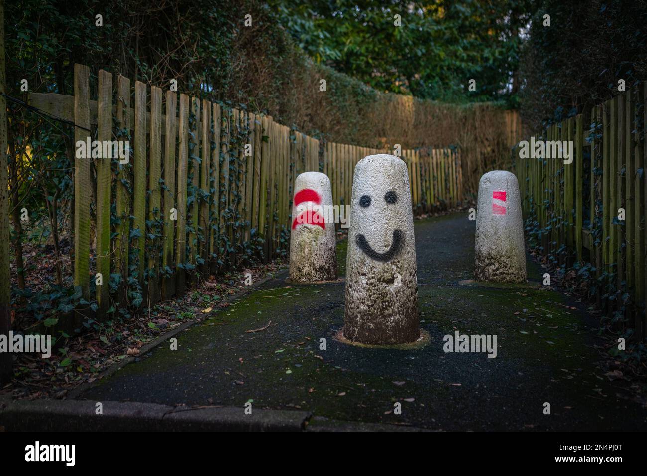 Betonpoller mit lustigen Gesichtern, die darauf gemalt sind, um Fahrzeuge daran zu hindern, einen Fußgängerweg zu betreten, England, Großbritannien Stockfoto