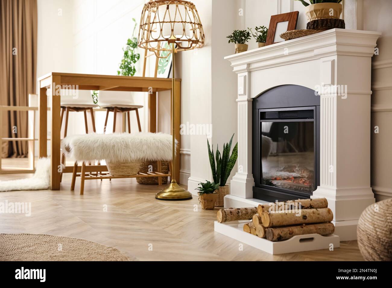 Eleganter knstlicher Kamin und Holztisch im Zimmer. Innendesign  Stockfotografie - Alamy