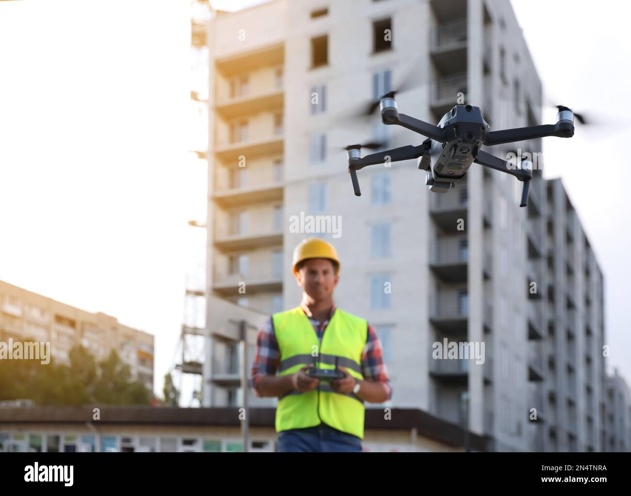 Bauarbeiter, die Drohne mit Fernsteuerung auf der Baustelle bedienen. Luftaufnahmen Stockfoto