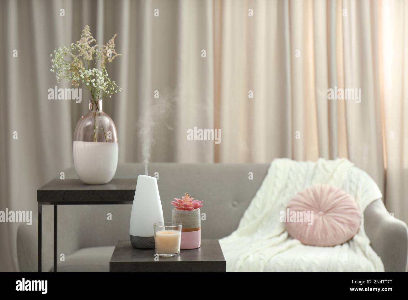 Aroma-Öl-Diffusor und Kerze auf dem Tisch im Raum Stockfoto