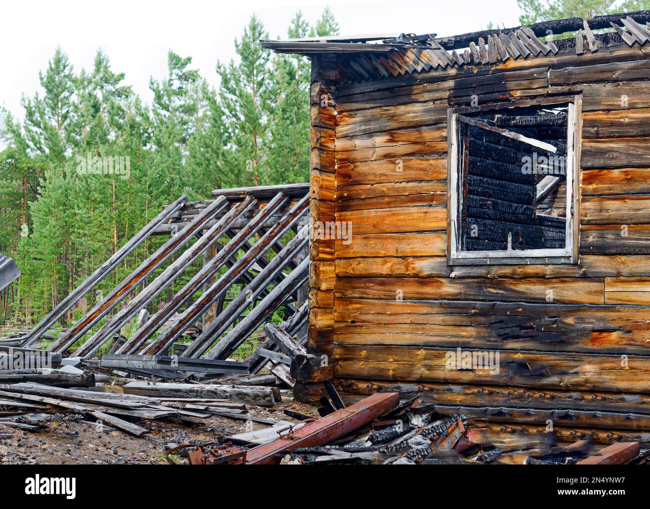 Die Überreste des verbrannten Holzrahmenhauses nach einem Brand mit Fenster und Dach des Gewächshauses in den Wäldern des Nordens von Yakutia. Stockfoto