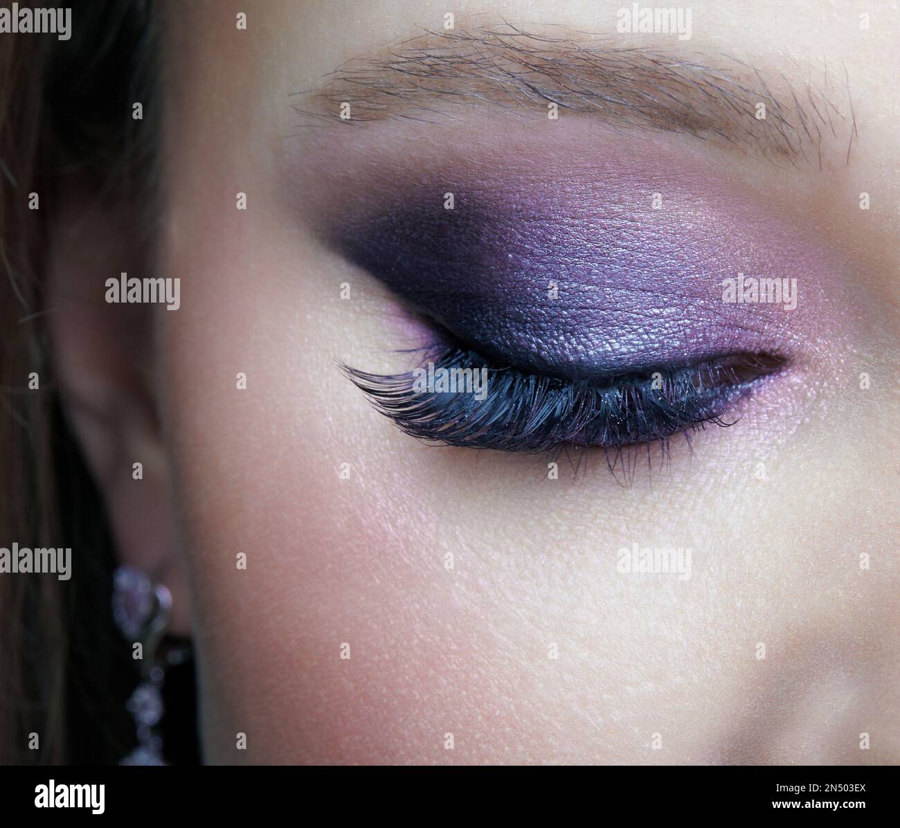 Makroaufnahme eines geschlossenen weiblichen Auges. Frau mit fliederfarbenem Schönheitsaugen-Make-up. Mädchen mit perfekter Haut und violetten, rauchigen Augenschatten. Stockfoto