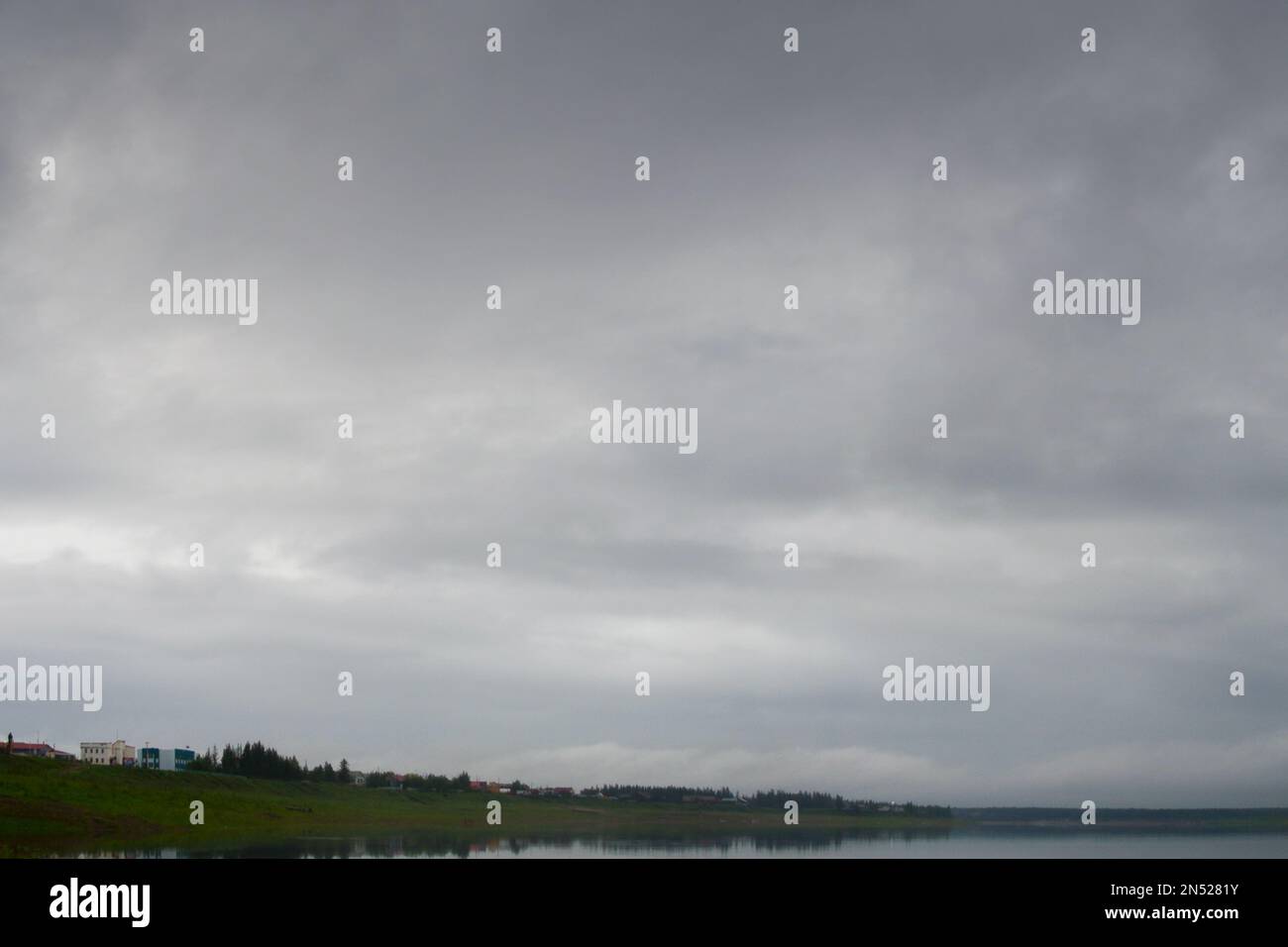 Fettgraue Wolken bei Sonnenuntergang hängen über den nördlichen Flüssen Viluy und den Häusern des Dorfes Yakut Suntar. Stockfoto