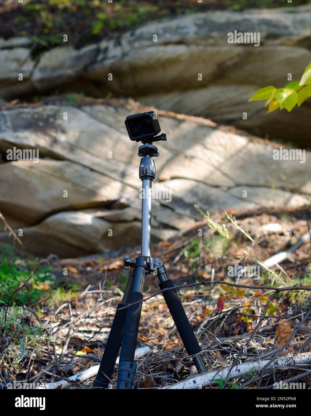 Die Action-Kamera steht auf einem Stativ und zeichnet Videos im Wald am prallen Felsen auf. Stockfoto
