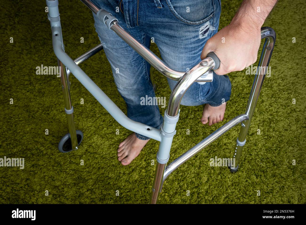 Ein kranker Mensch geht mit Hilfe von speziellen Geräten für die Rehabilitation. Walker für Erwachsene. Rehabilitation nach einem gebrochenen Bein oder Schlaganfall. Stockfoto