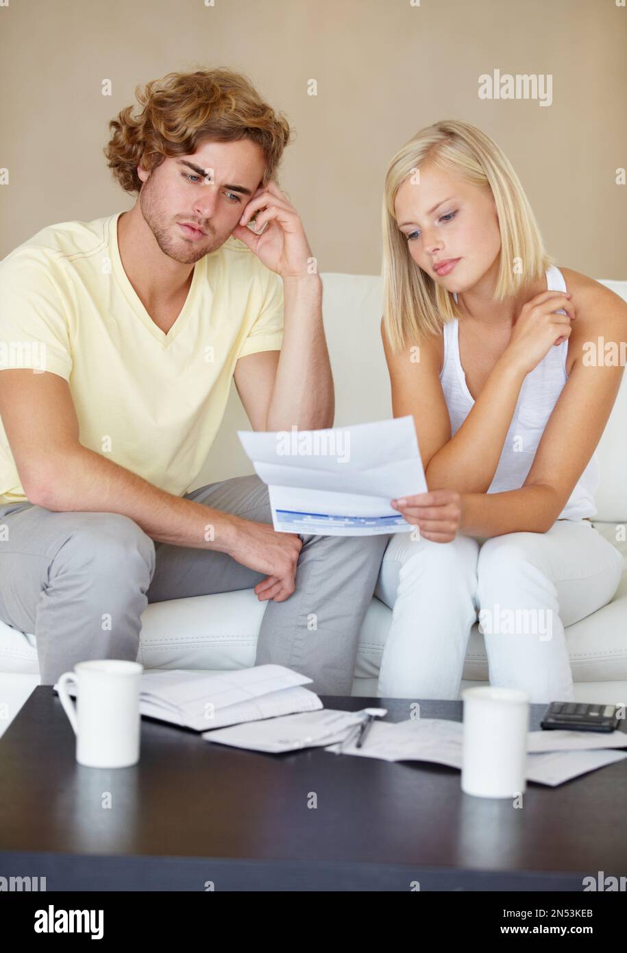 Das moderne Leben ist hart. Ein junges Paar, das zusammen in seiner Lounge einen Finanzbericht liest. Stockfoto