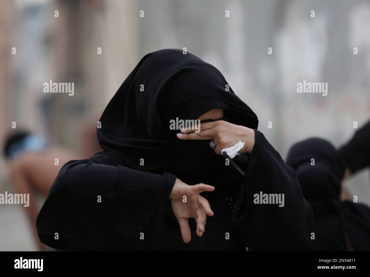 A Bahraini anti-government protester covers her eyes against tear gas ...