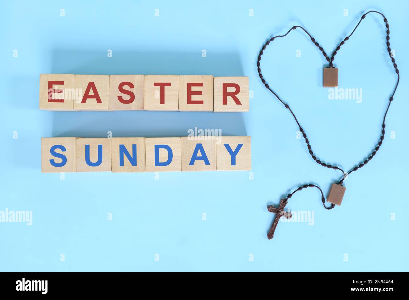Ostersonntag - Konzept der Heiligen Woche. Holzblocktypographie mit Rosenkranz auf blauem Hintergrund. Stockfoto